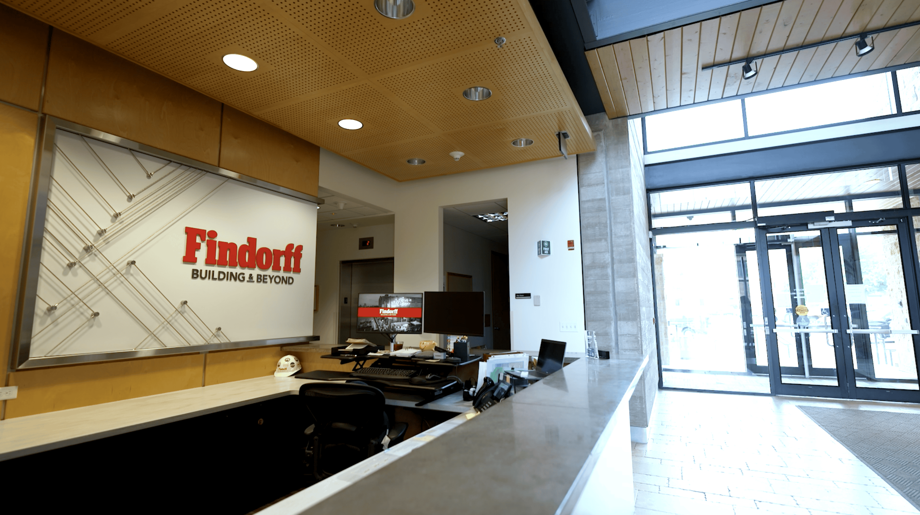 A reception desk in a modern office setting featuring the Findorff logo on a wall behind it. The logo reads 